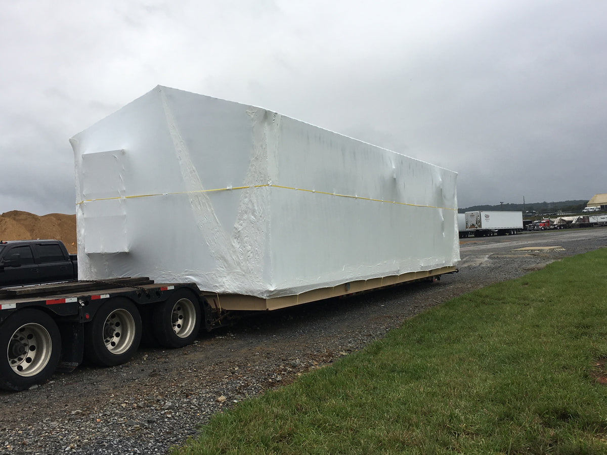 Large shrink-wrapped cargo secured on a flatbed trailer at a Pro Shrink Wrap job